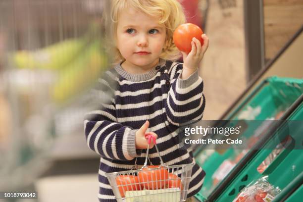 toddler picking tomatoes in supermarket - children fruit stock-fotos und bilder