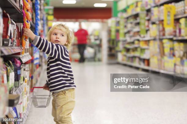 toddler picking something from shelf in supermarket - dieb stock-fotos und bilder