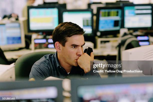 broker watching stock and holding phone - banking rooms stock pictures, royalty-free photos & images