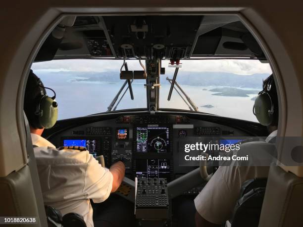 pilot and co-pilot piloting aeroplane from airplane cockpit - piloter photos et images de collection