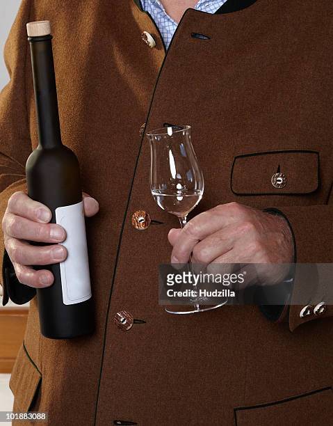 a man holding a bottle and glass of schnapps - grappa stock-fotos und bilder