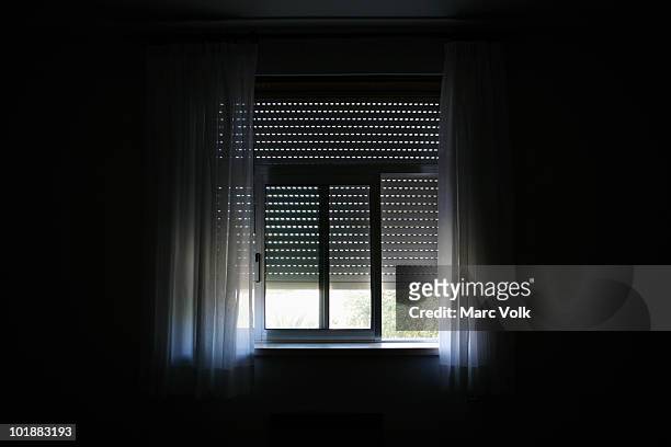 sunlight coming in a window in a darkened room - fensterladen stock-fotos und bilder