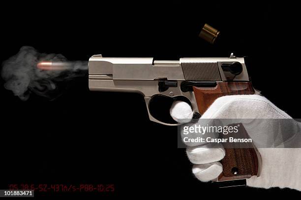 a gloved hand firing a gun - feuerwaffen abzug stock-fotos und bilder