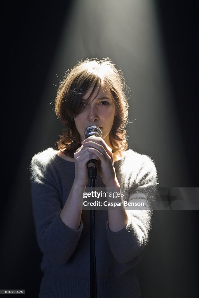 A Woman Standing Behind A Microphone