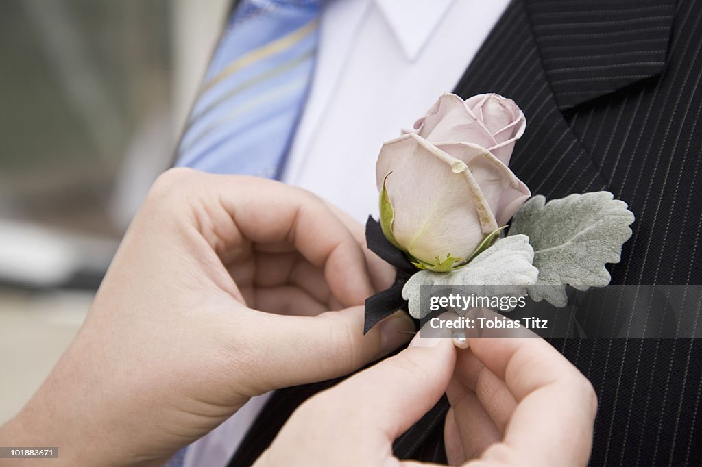 Detail of a woman pinning a corsage to a jacket lapel,  Melbourne, Victoria, Australia