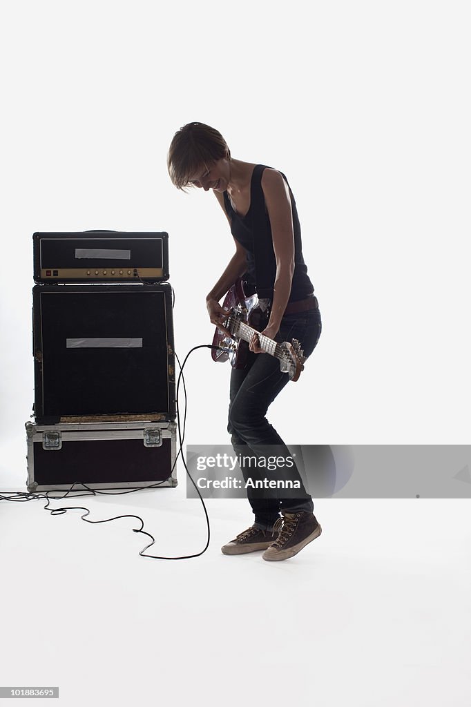 A woman playing electric guitar, studio shot, white background, back lit