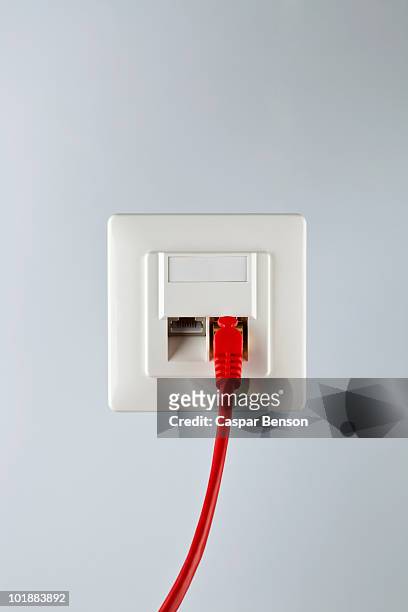 a network cable plugged into a wall socket - plug stock-fotos und bilder