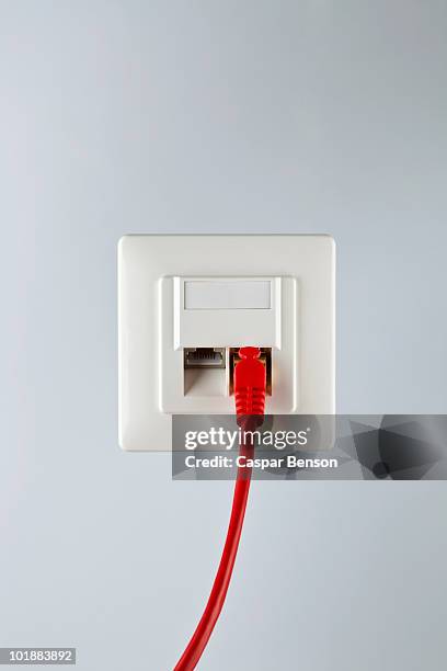 a network cable plugged into a wall socket - internet cable stock pictures, royalty-free photos & images