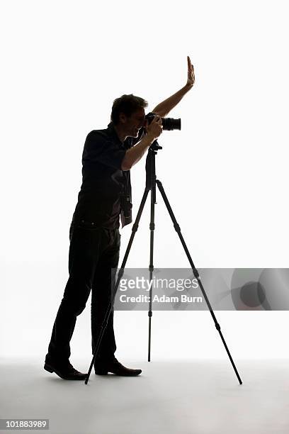 a photographer working with a camera on a tripod - tripod ストックフォトと画像
