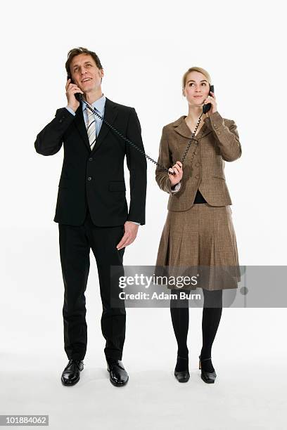 two business people using phone receivers connected with the same cord - telefone fixo imagens e fotografias de stock