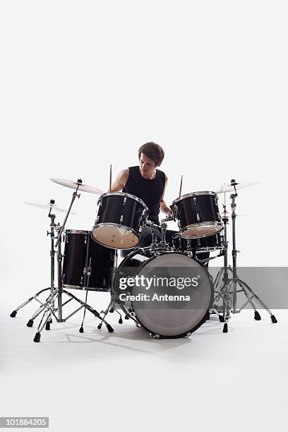 a man on drums performing, studio shot, white background, back lit - drum photos et images de collection