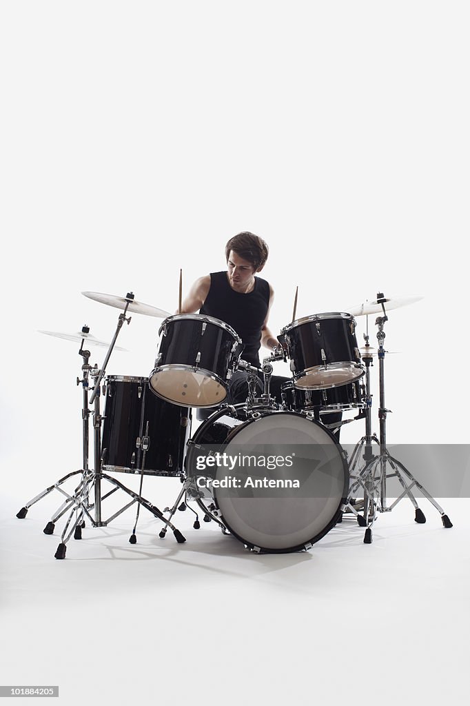 A man on drums performing, studio shot, white background, back lit