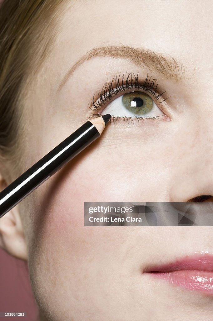 A woman applying eyeliner, detail of eye