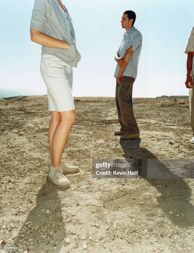 THREE YOUNG PEOPLE STANDING ON DIRT