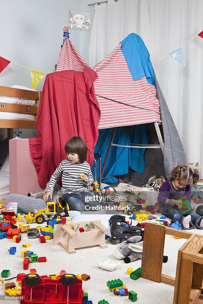 A young boy and girl playing in a bedroom