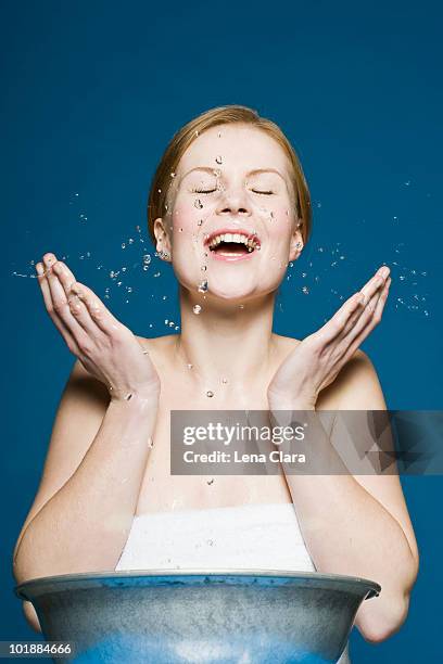 a woman washing her face - bassine photos et images de collection