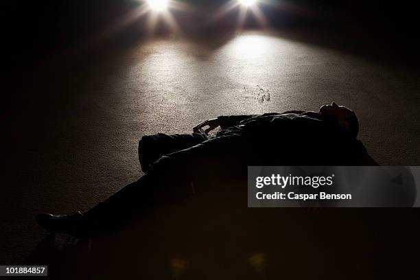 a man lying on the ground in front of a car at night - roadkill 個照片及圖片檔