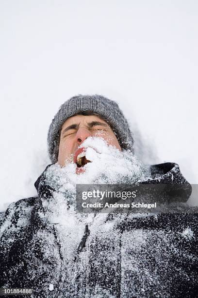 a man lying on back after being hit with a snowball, head and shoulders - funny snow stock-fotos und bilder