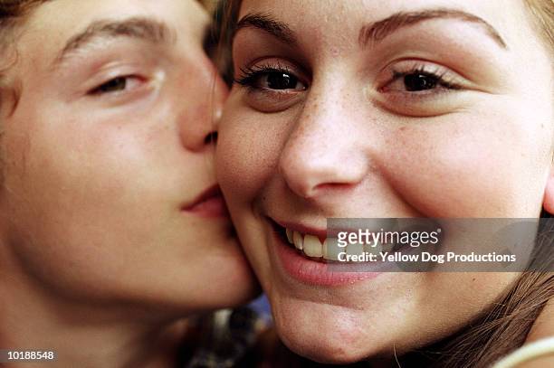 teenage boy(14-16) kissing girl on cheek - couple portrait fotografías e imágenes de stock