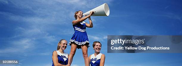 two cheerleaders supporting third cheerleader with megaphone - ragazza pon pon foto e immagini stock