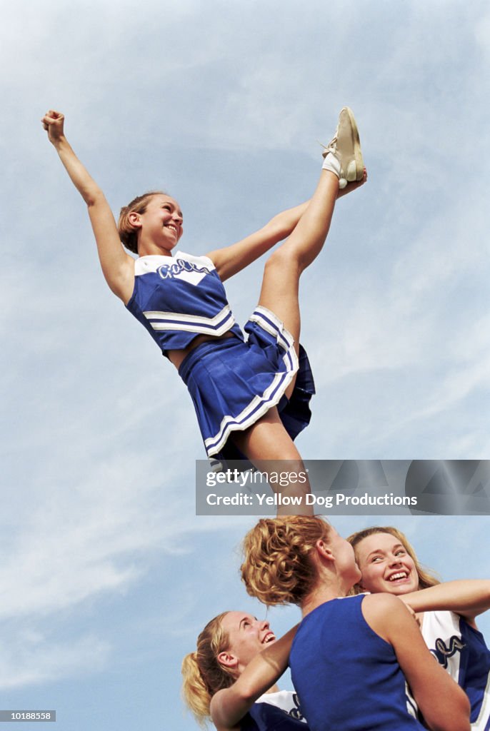 Cheerleader with leg raised on pyramid