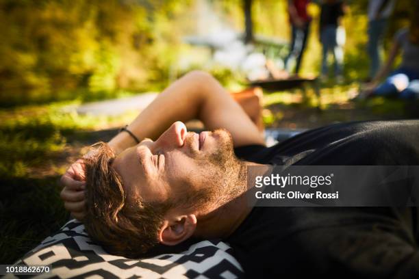 relaxed man lying outdoors on cushion - low key stock-fotos und bilder