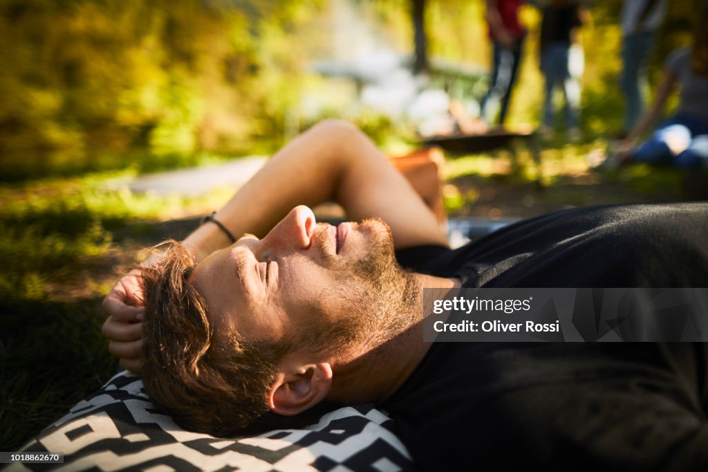 Relaxed man lying outdoors on cushion