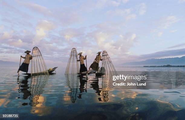 three fiisherman standing on boats holding fish traps - entwicklungsland stock-fotos und bilder