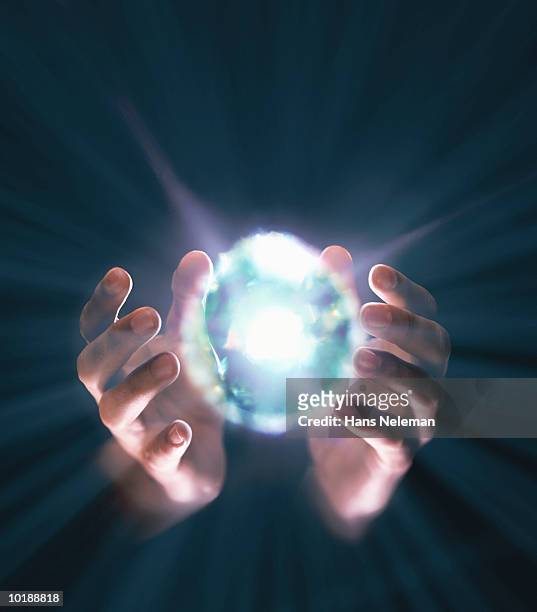 hands coming around bright ball of light - magic ball fotografías e imágenes de stock