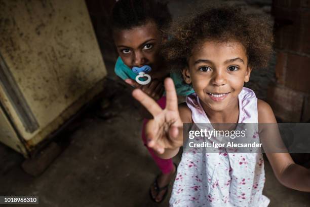 brazilian little girl making two or v sign with her fingers - slum stock pictures, royalty-free photos & images