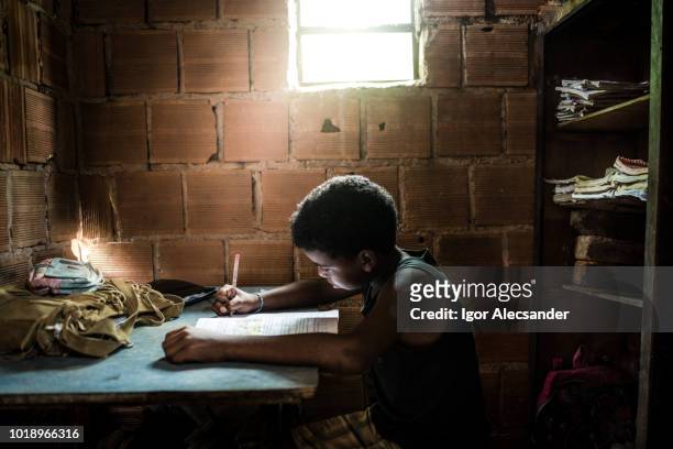 braziliaanse jongen thuis studeren - teenager learning child to read stockfoto's en -beelden