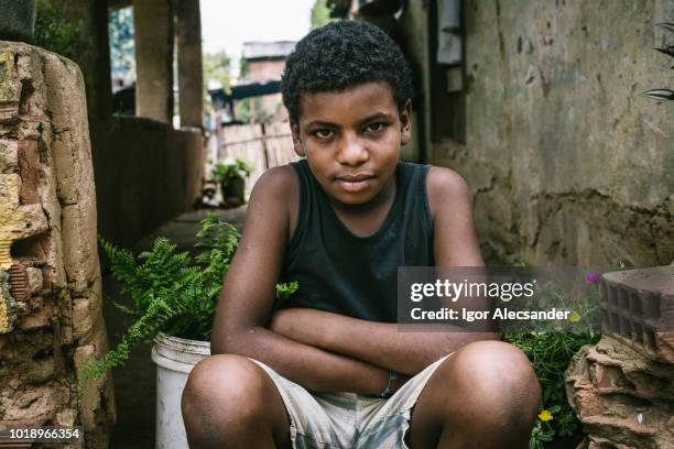 brasilianische junge sitzt auf der veranda des hauses - favela stock-fotos und bilder