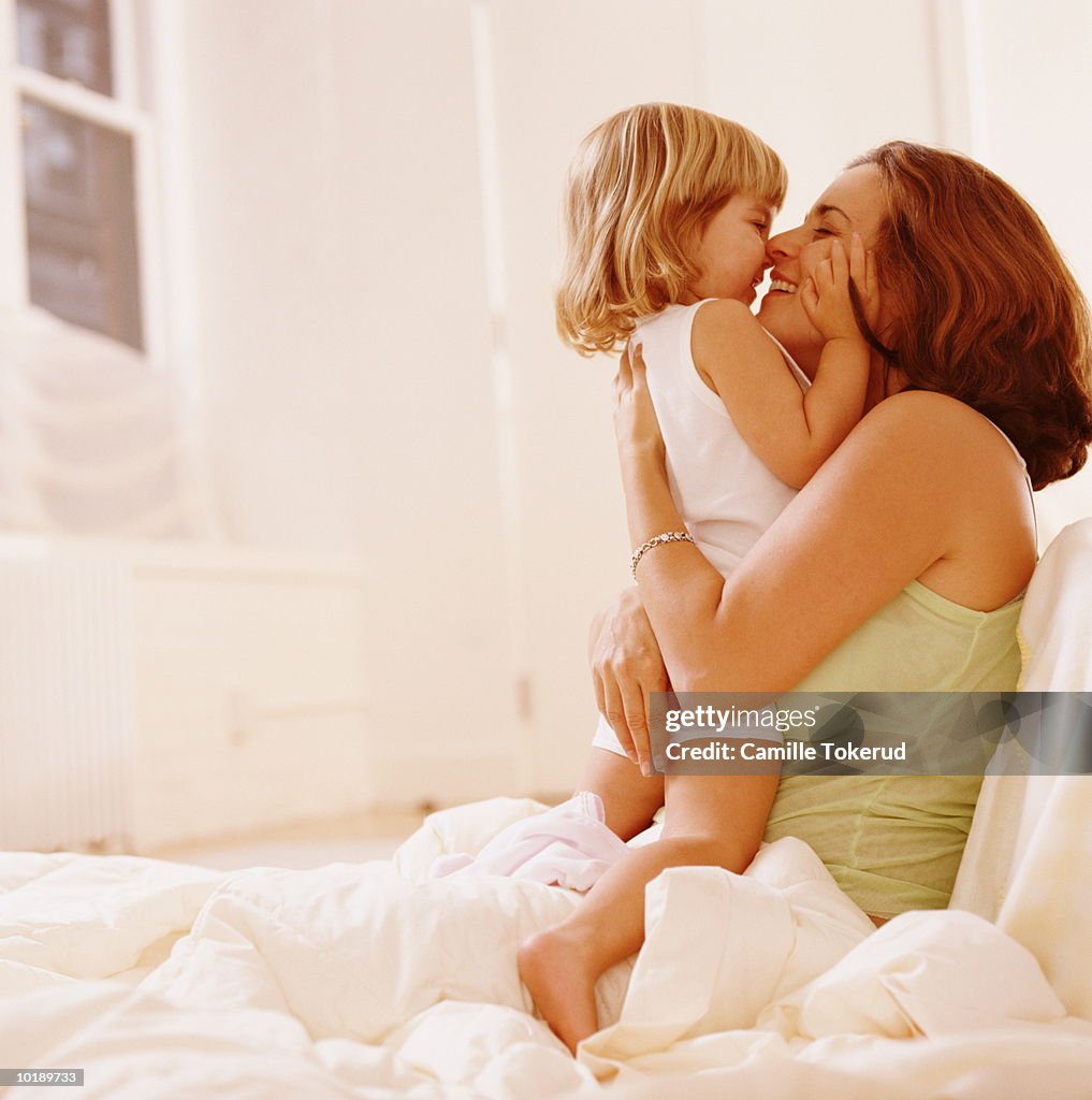 Mother and daughter (2 years) hugging in bed