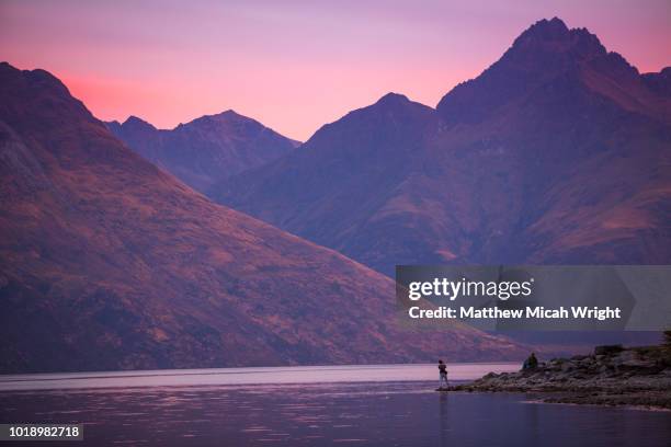 people watch as sunset descends over queenstown's lake wakatipu. the remarkable mountain ranges loom in the background. - queenstown new zealand stock pictures, royalty-free photos & images