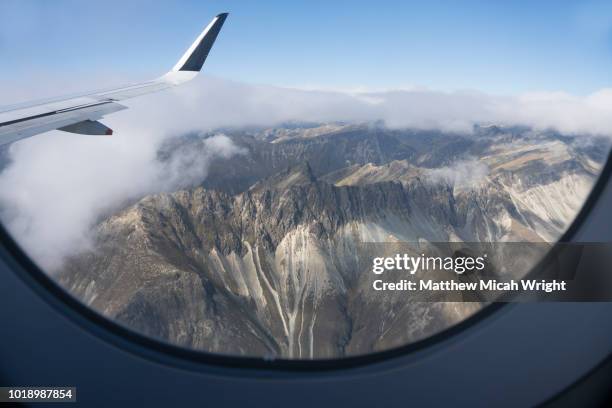 a view from an airplane window as it flies over new zealand's south island mountain passes. - plane wing stock pictures, royalty-free photos & images