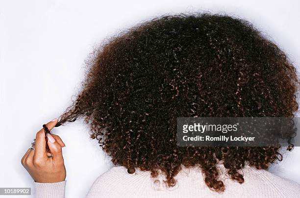 young woman twisting hair round finger, rear view - afro frisur stock-fotos und bilder
