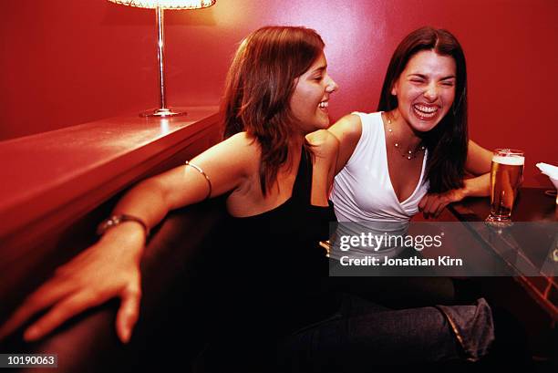 two young women laughing and having beers in nightclub - girls night stock-fotos und bilder