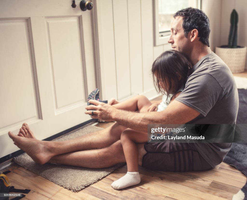 Father Putting Shoes On Toddler Daughter