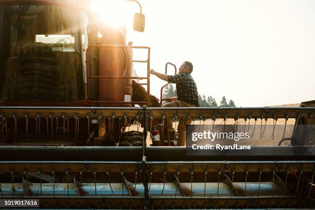 agriculteur, escalade en à la moissonneuse batteuse dans le champ de blé de l’idaho - champs tracteur photos et images de collection