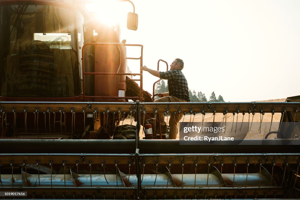 Farmer Climbing In To Combine Harvester In Idaho Wheat Field