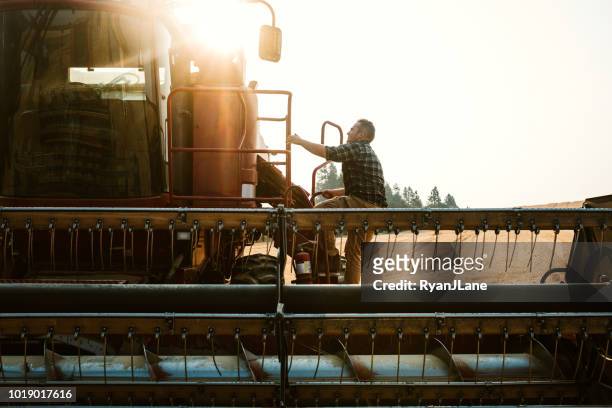 farmer climbing in to combine harvester in idaho wheat field - harvesting stock pictures, royalty-free photos & images