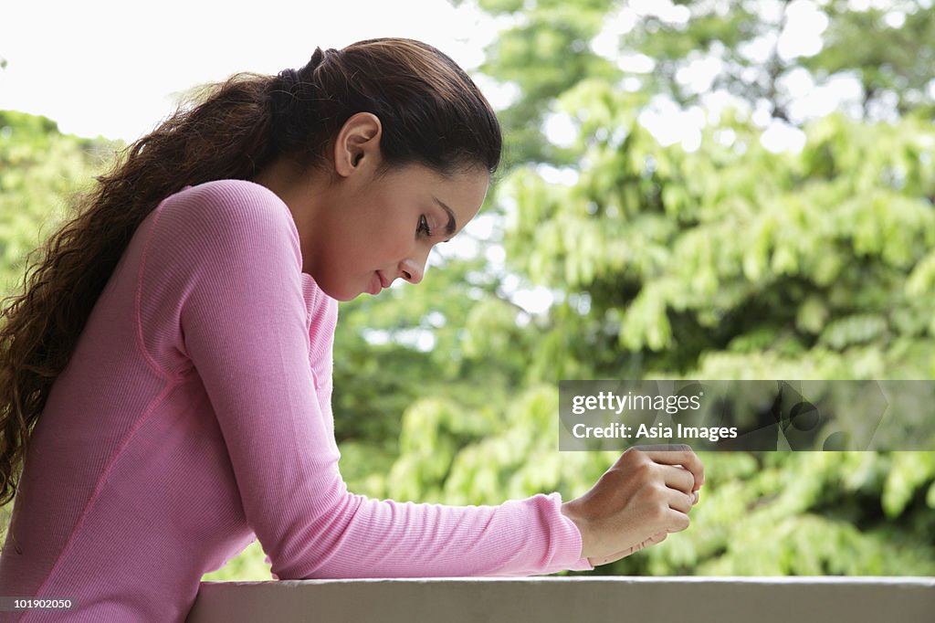 Young woman leaning on balcony looking down