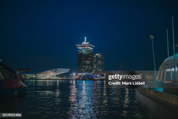 ferry boats on the amstel river at night with view to the eye film institute and a'dam tower, north district, amsterdam, north holland, netherlands, europe - amsterdam night stock pictures, royalty-free photos & images