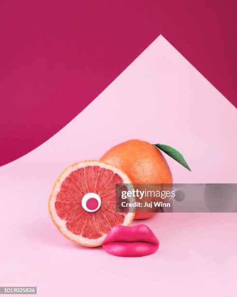 surreal pink grapefruit with eye and lips on pink background - orange couleur photos et images de collection