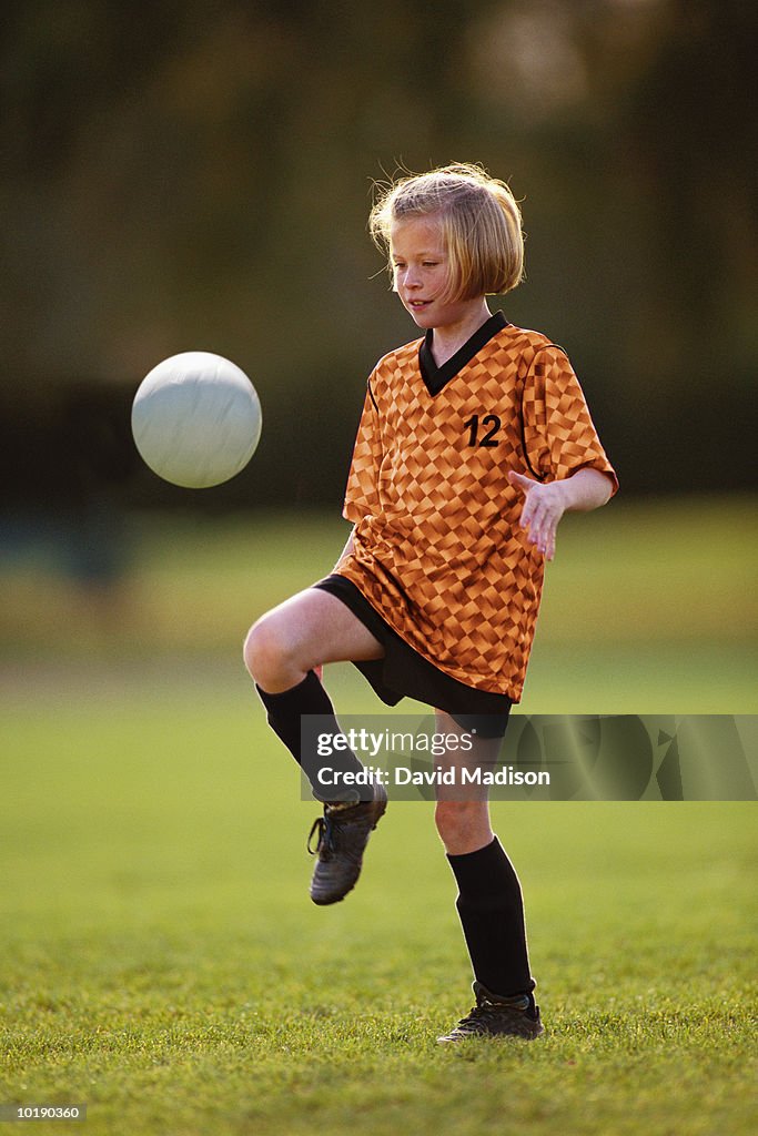 Girl (9-11) kicking soccer ball