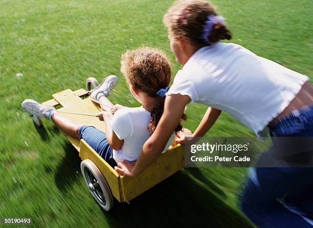 two girls (8-10) playing with go-cart - soapbox cart stock pictures, royalty-free photos & images