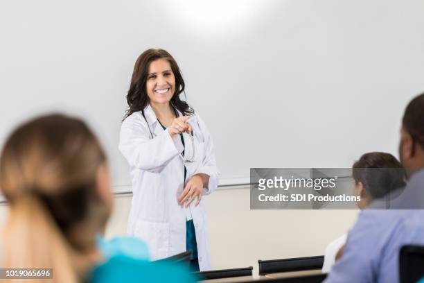 smiling medical professor points to student during lecture - doctor presentation stock pictures, royalty-free photos & images