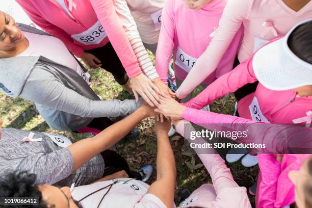 group of unrecognizable race for the cure participants stack hands - fundraising concept stock pictures, royalty-free photos & images