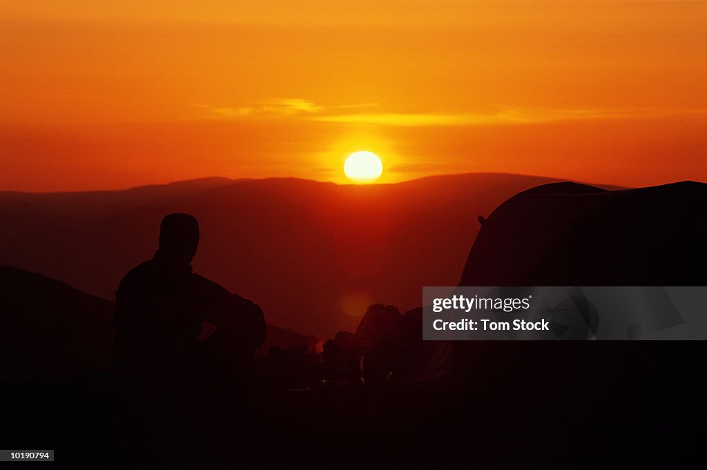 UK, Cumbria, Lake District, Coniston Fells, male camper cooking outsid
