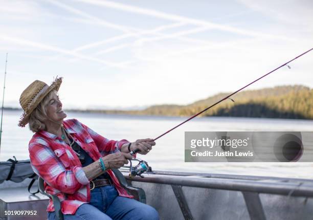 active senior woman trout fishing from aluminum boat on a lake - aluminum boat stock-fotos und bilder